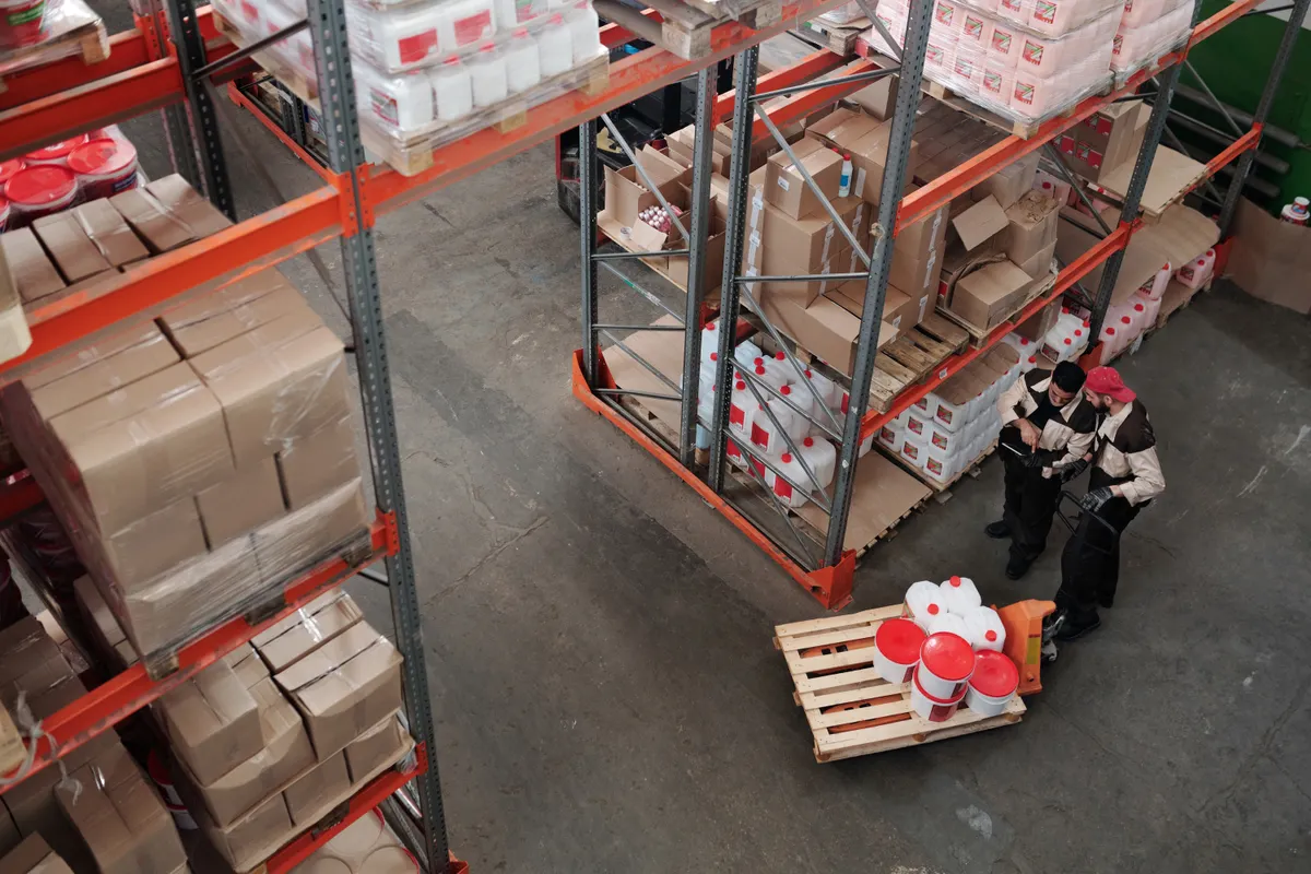 Dos trabajadores revisando mercancía en un almacén, fotografía de stock
