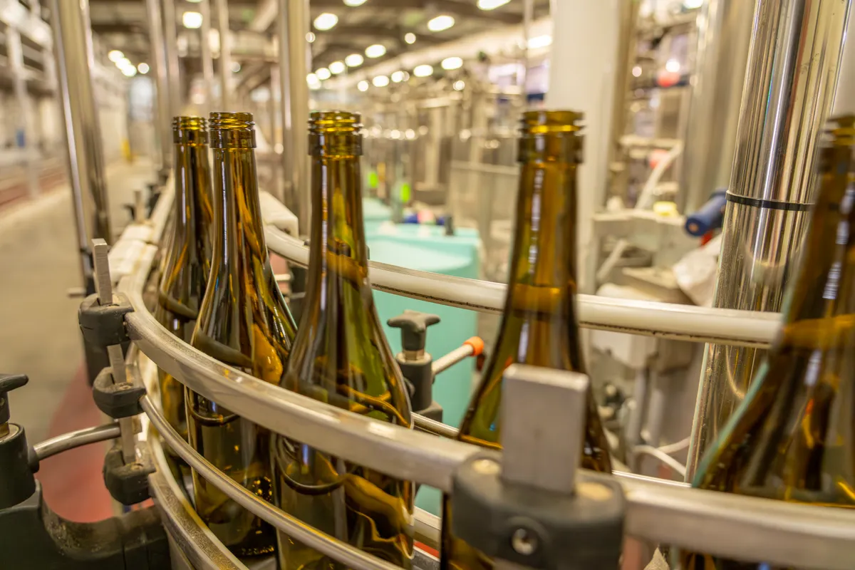Botellas de vidrio en una línea de producción, fotografía de stock