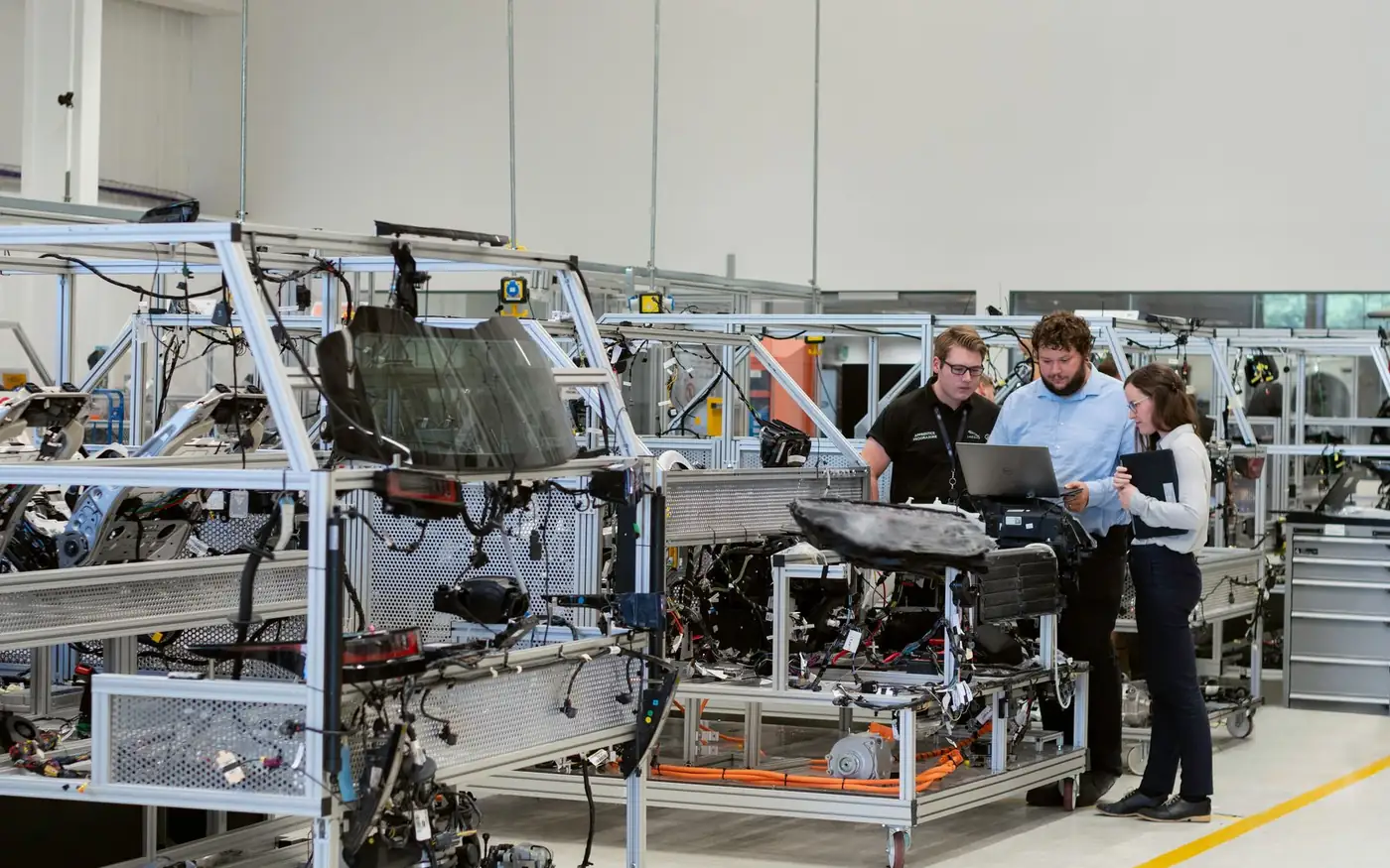 Tres profesionales revisando un prototipo y datos técnicos en un taller de ingeniería